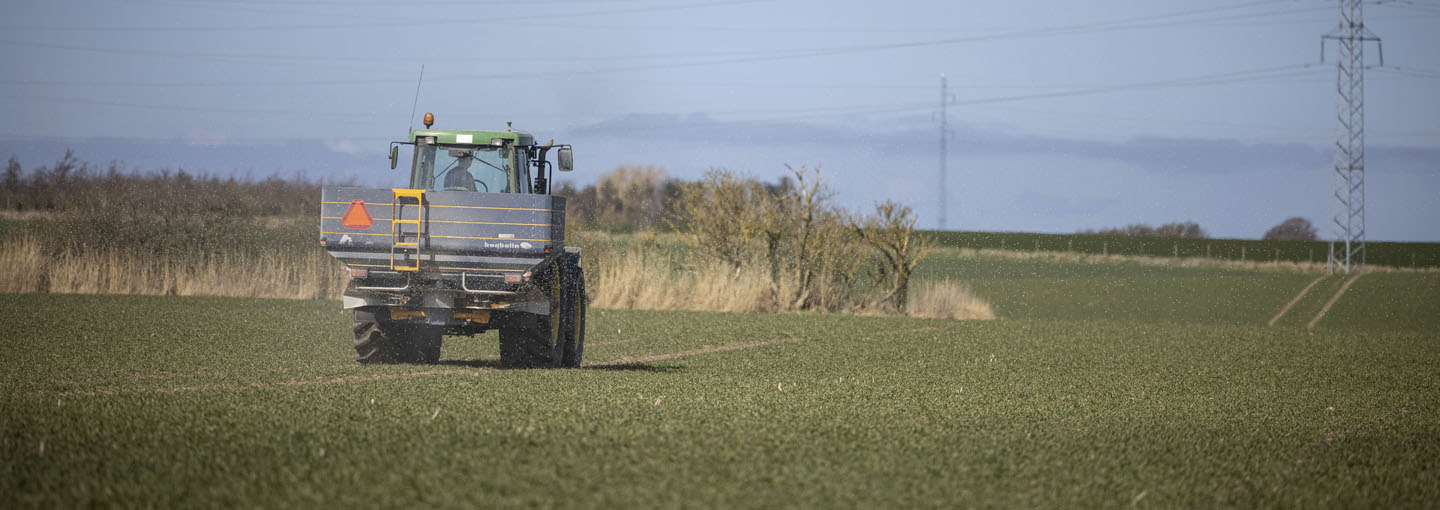 Traktor på forårsmark med gødningsspreder