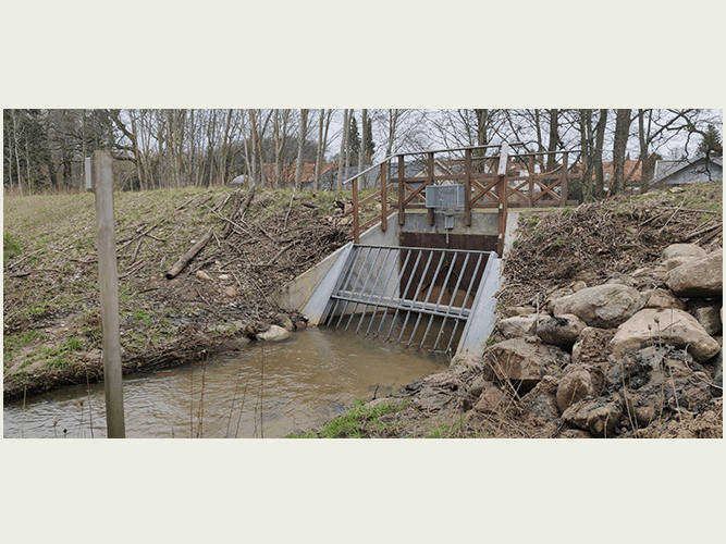 Dige med vandbremse med gitterforanstaltning til at bremse grene, blade og andre store genstande