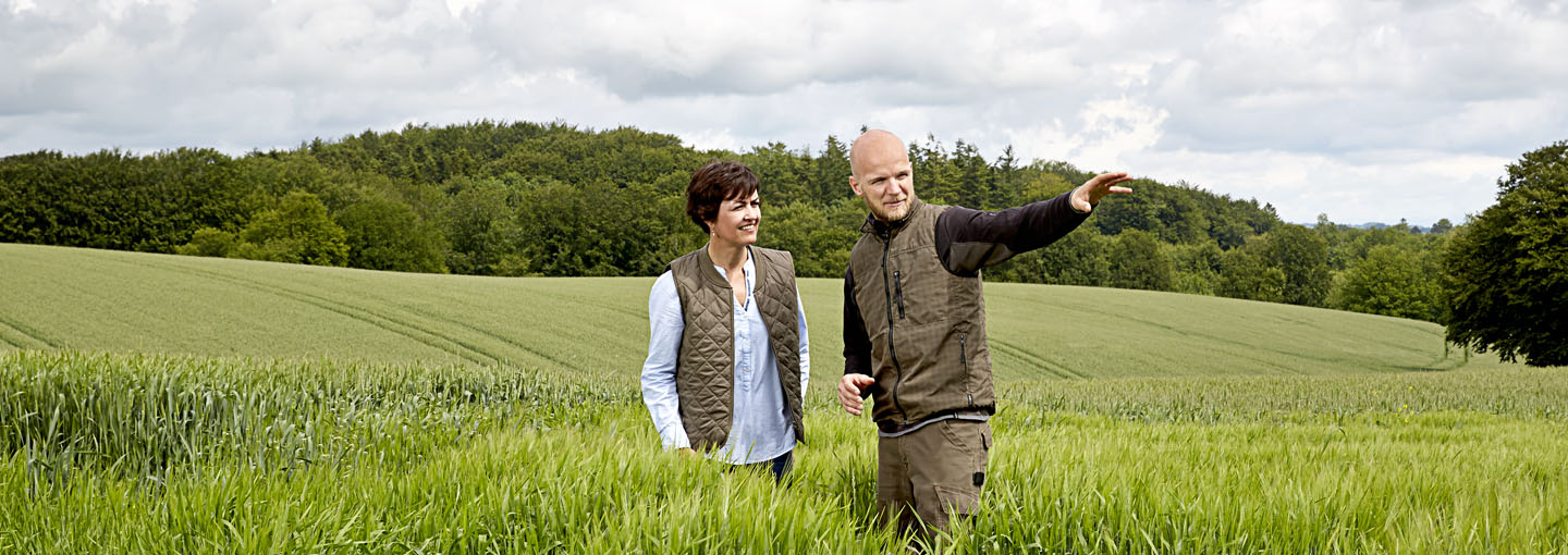 Landmand står sammen med en konsulent og skuer ud over marker