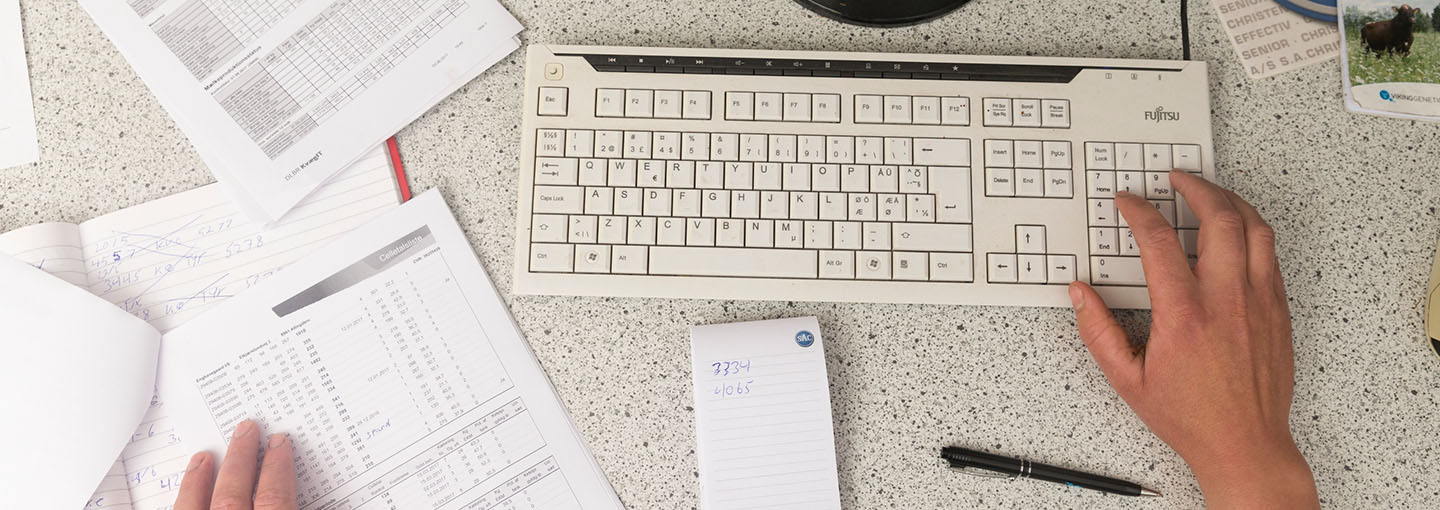 Skrivebord med tastatur og papirer
