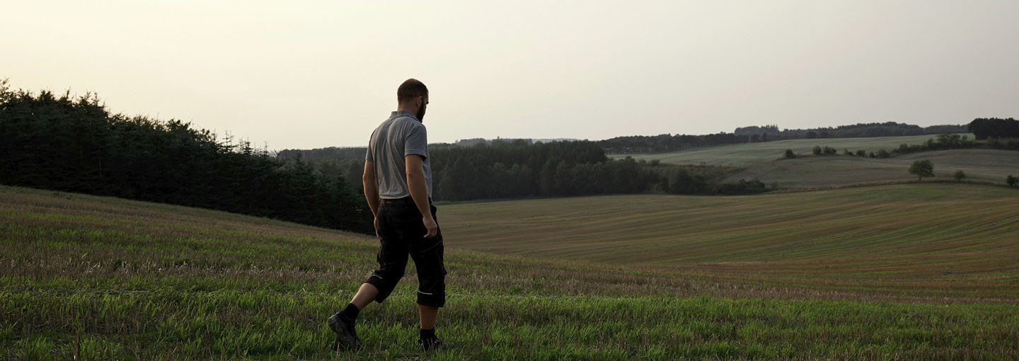Landmand vandrer ud over sine marker i skumringstid