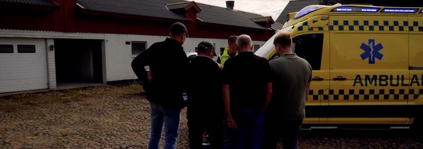 medarbejdere på en gård står ved en ambulance
