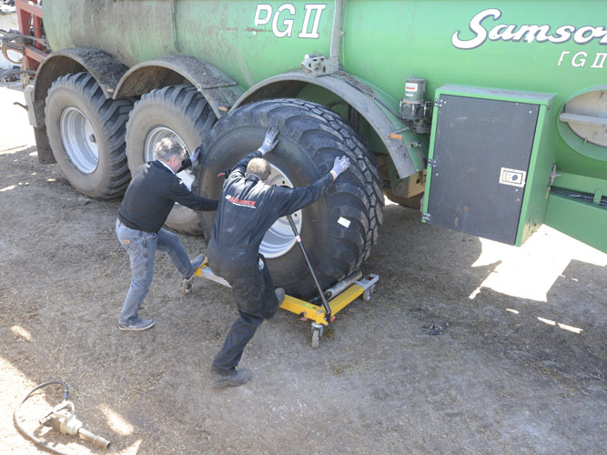 To mænd monterer store VF_dæk på grøn gyllevogn