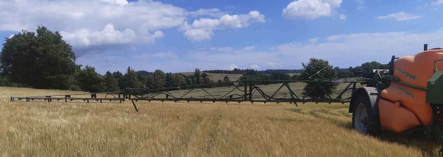 Kornmark hvor man se en side af en marksprøjte